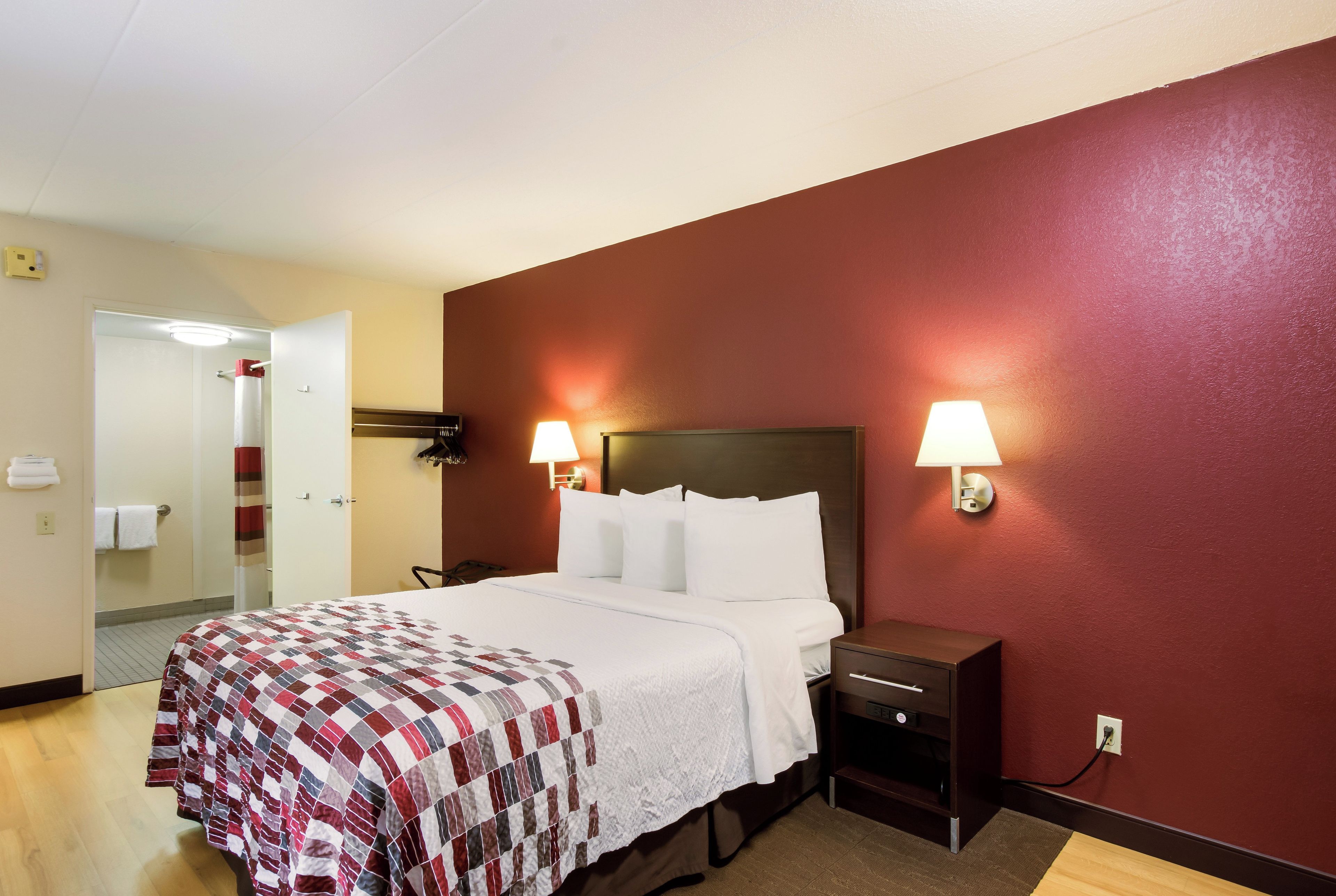 Una habitación de hotel con una cama, dos lámparas de noche, una mesita de noche y un espejo.