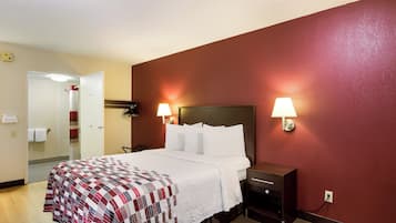 A hotel room with a bed, two bedside lamps, a nightstand, and a mirror.