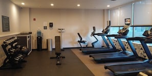 A gym with treadmills, dumbbells, and a water dispenser.