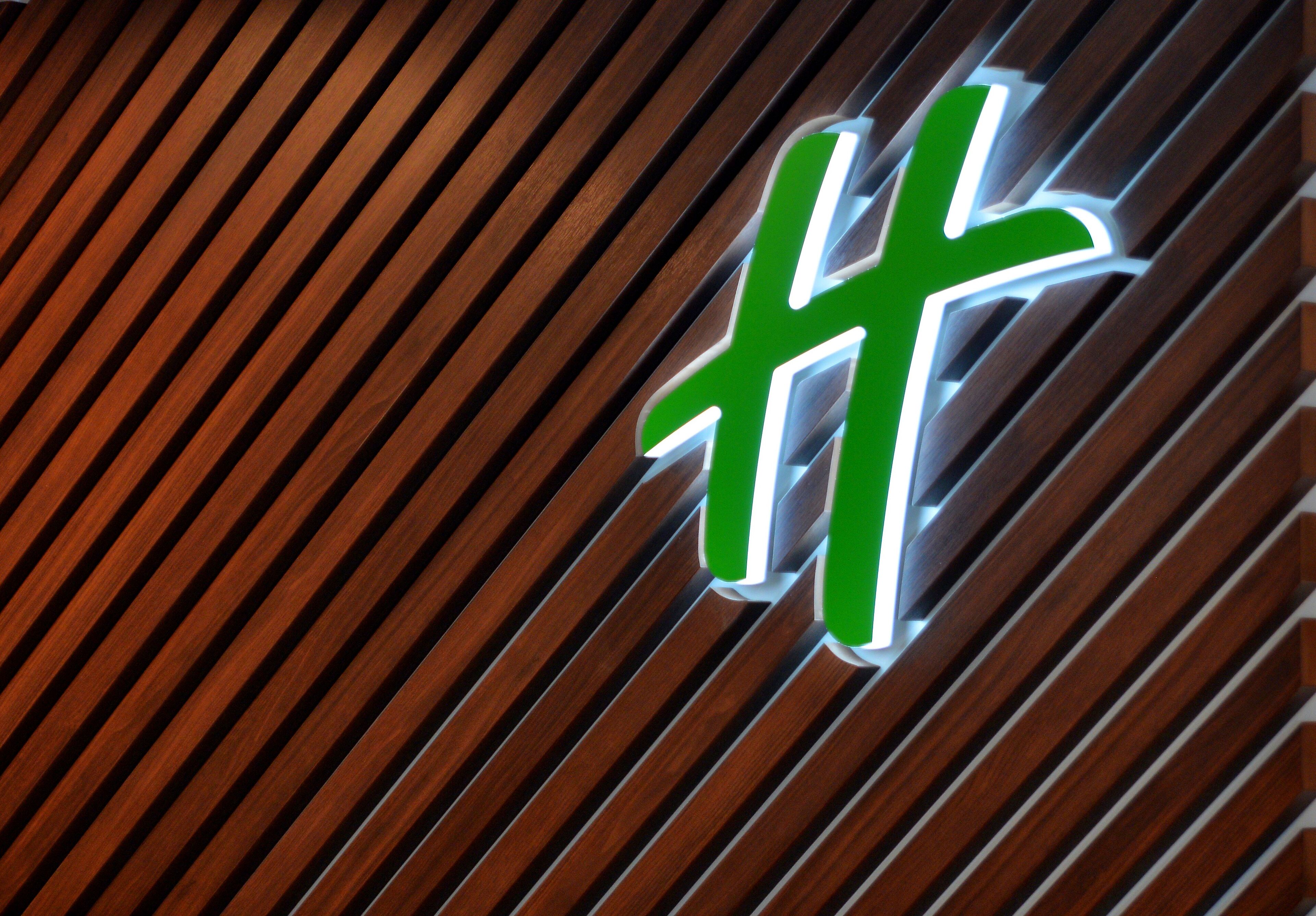 A green and white sign with a cross symbol on a wooden slatted background.