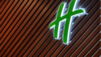 A green and white sign with a cross symbol on a wooden slatted background.