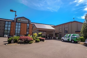 A Holiday Inn with a modern building, a parking lot, and a van. - Holiday Inn Portland- I-5 S (Wilsonville) by IHG (Wilsonville)
