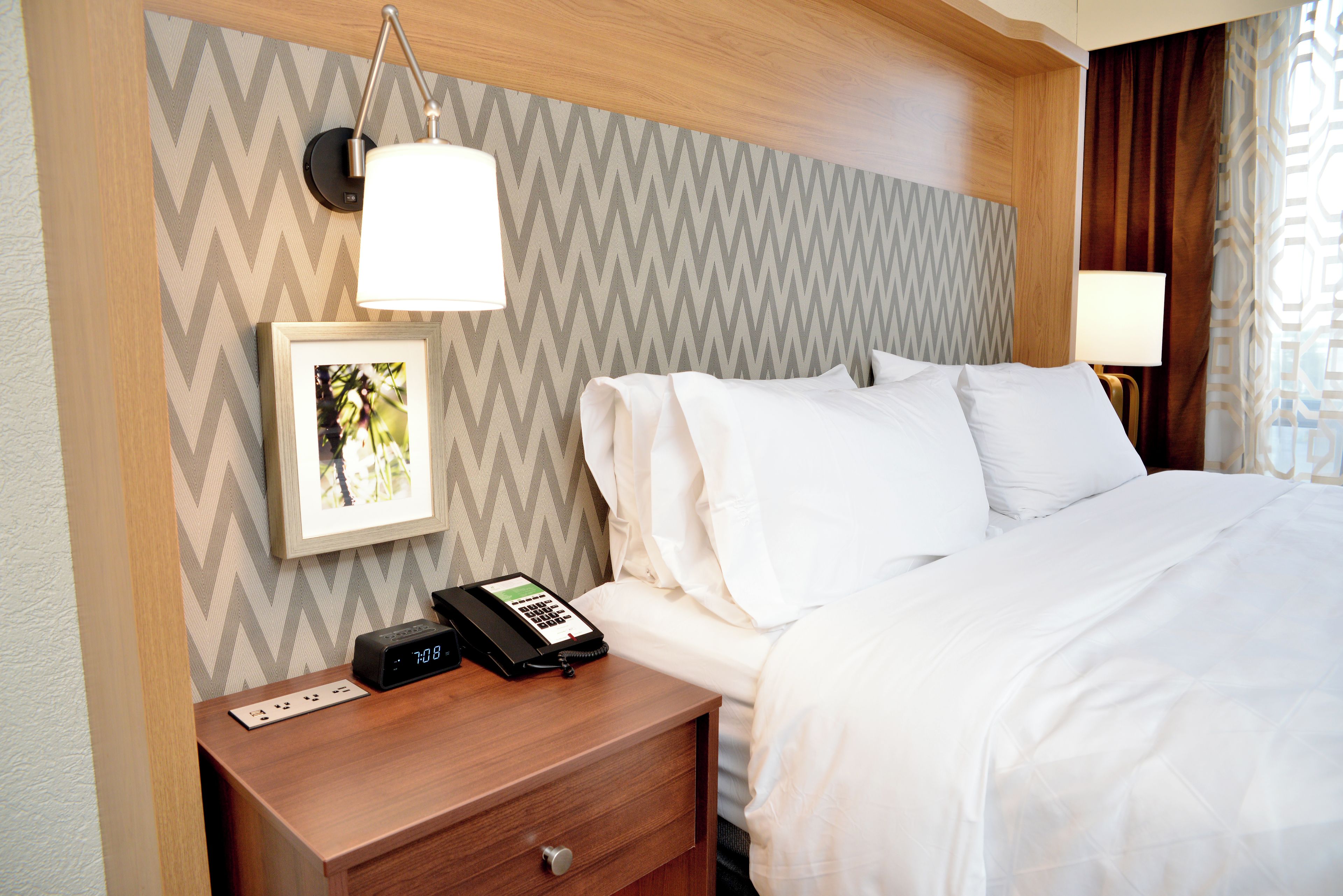 A hotel room with a bed, bedside table, lamp, and a telephone.