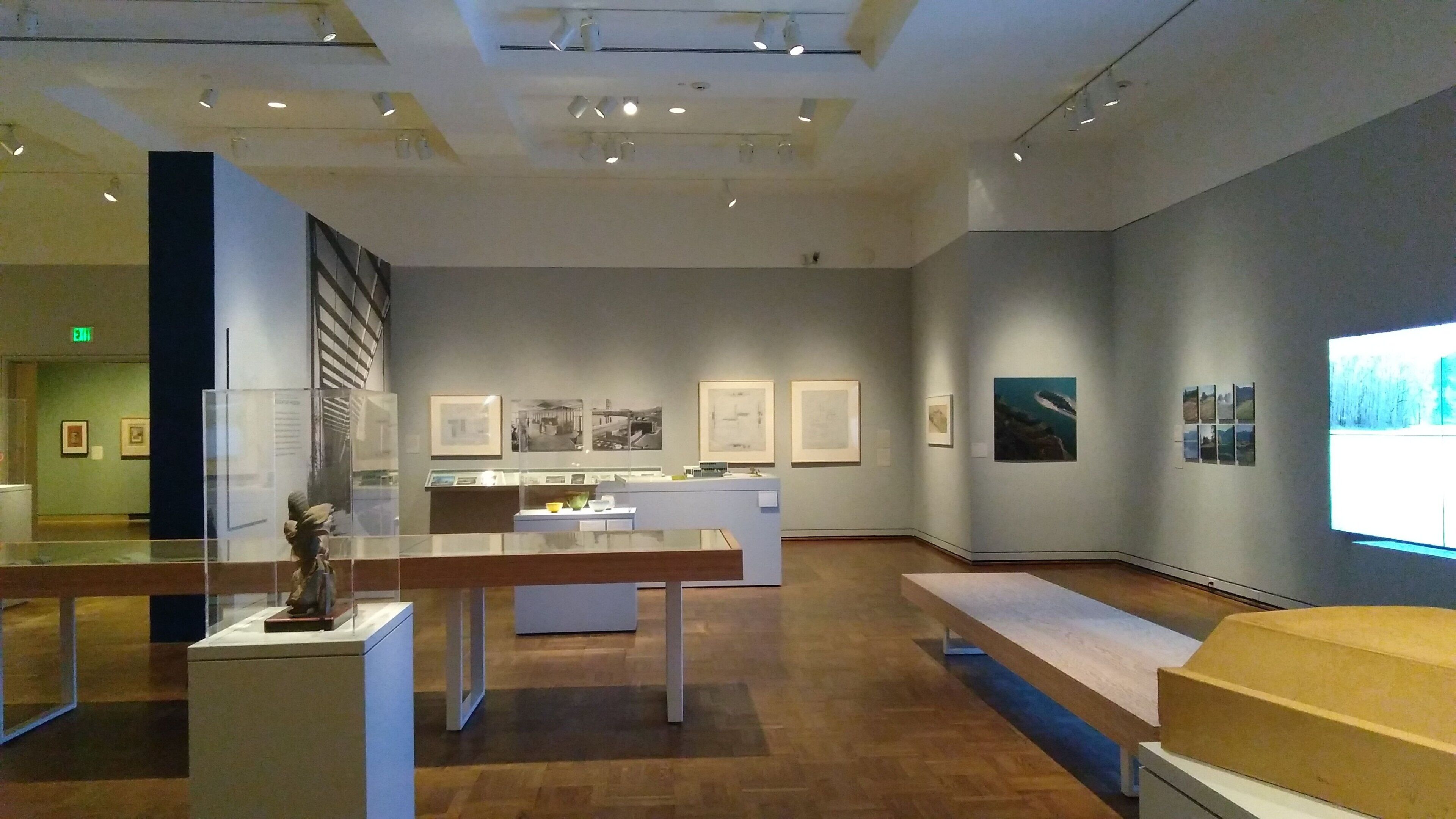 Une galerie d’art dotée de planchers en bois, de vitrines et de tableaux encadrés accrochés aux murs.