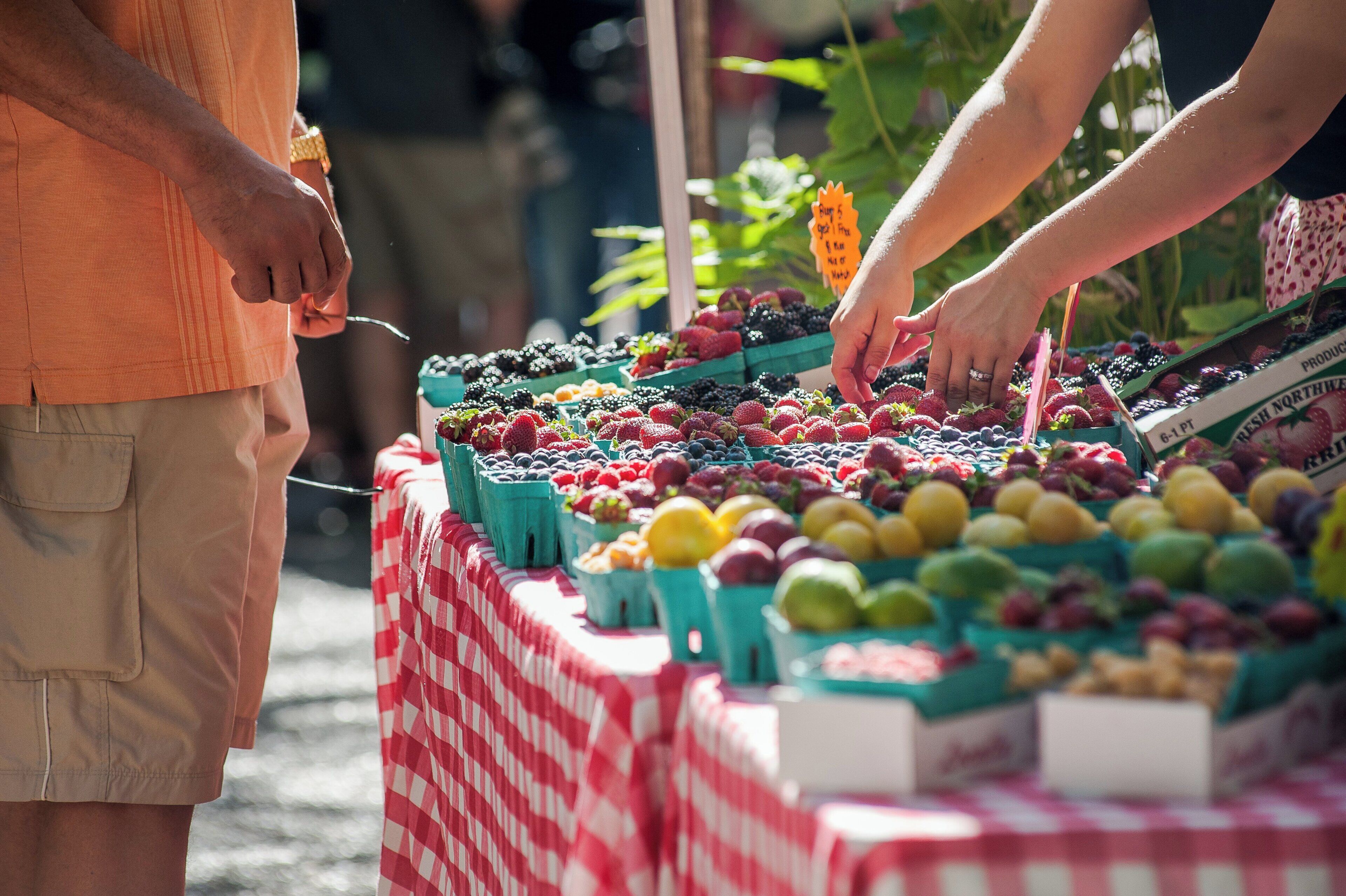 Un étal de marché où sont exposés divers fruits et légumes dans des caisses vertes.