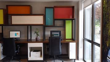 A modern office desk with two computer monitors, a printer, and a potted plant.