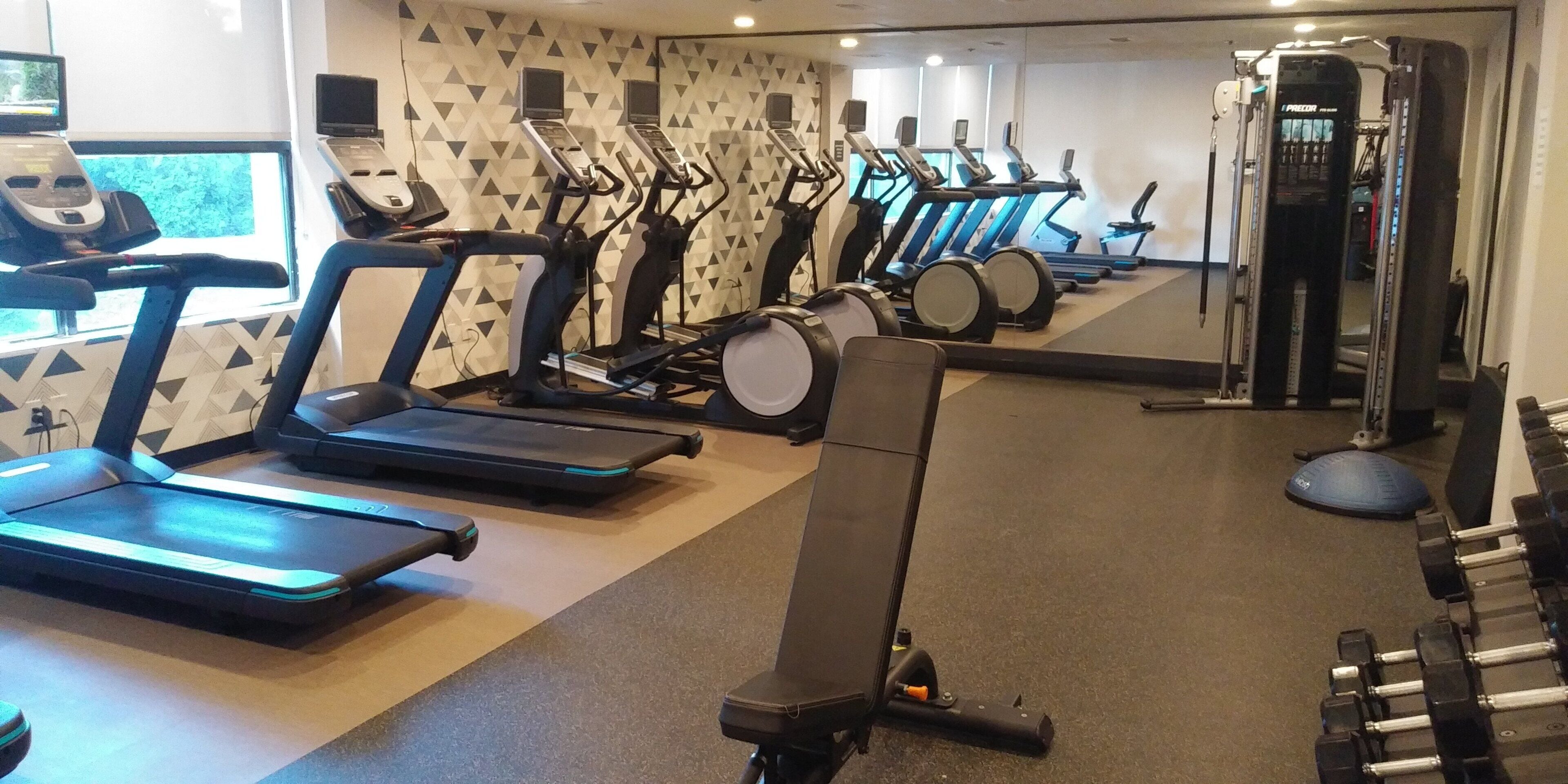 A gym with treadmills, elliptical machines, and weightlifting equipment.