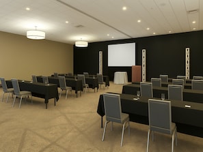 A conference room with multiple tables and chairs, a projector screen, and a podium.