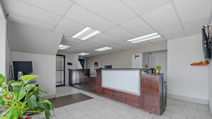 A reception area with a reception desk, potted plants, and a whiteboard. - Budget Inn Norfolk Va (Norfolk)