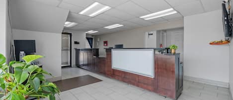 A reception area with a reception desk, potted plants, and a whiteboard.