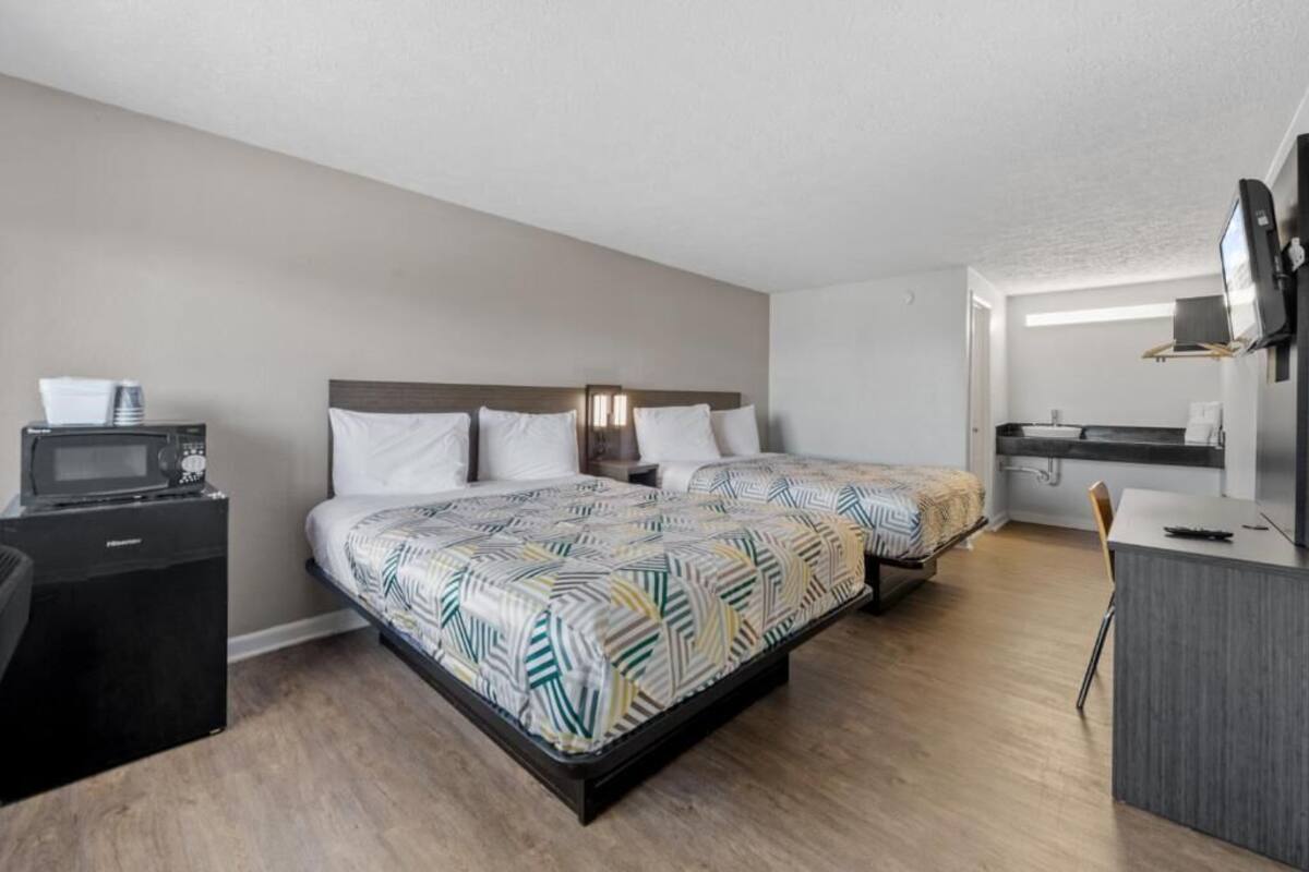 A hotel room with a bed, a desk, a microwave, and a TV.