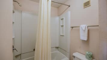 A bathroom with a shower curtain, a toilet, and a towel rack.