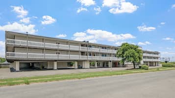 A multi-story motel with a central courtyard, a parking lot, and a clear sky.