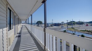 A long, covered balcony with a view of a parking lot and buildings in the distance. - Budget Inn Norfolk Va (Norfolk)