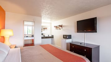Une chambre d’hôtel comprenant un lit, un bureau avec une lampe, une télévision, une commode et un miroir.