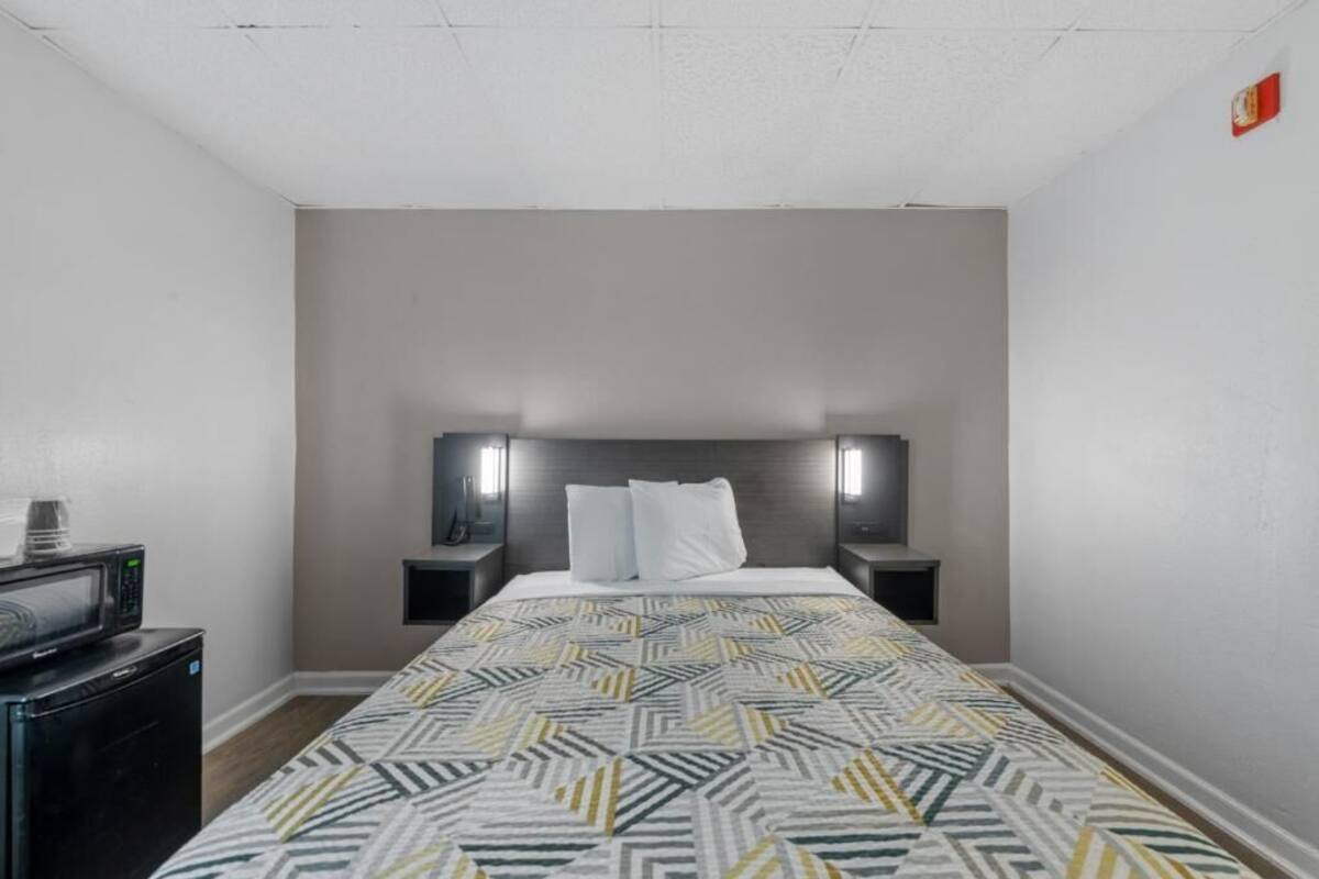A hotel room with a bed, two bedside tables, a microwave, and a small TV.