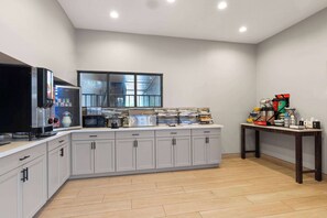A modern kitchen with grey cabinets, a large window, and a coffee station.