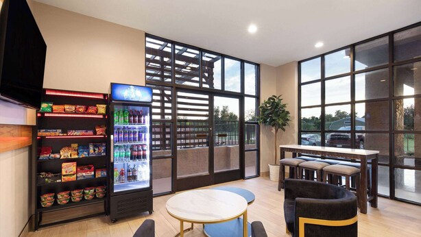 A modern interior with a seating area, a vending machine, and large windows. - Ramada by Wyndham Bainbridge (Bainbridge)
