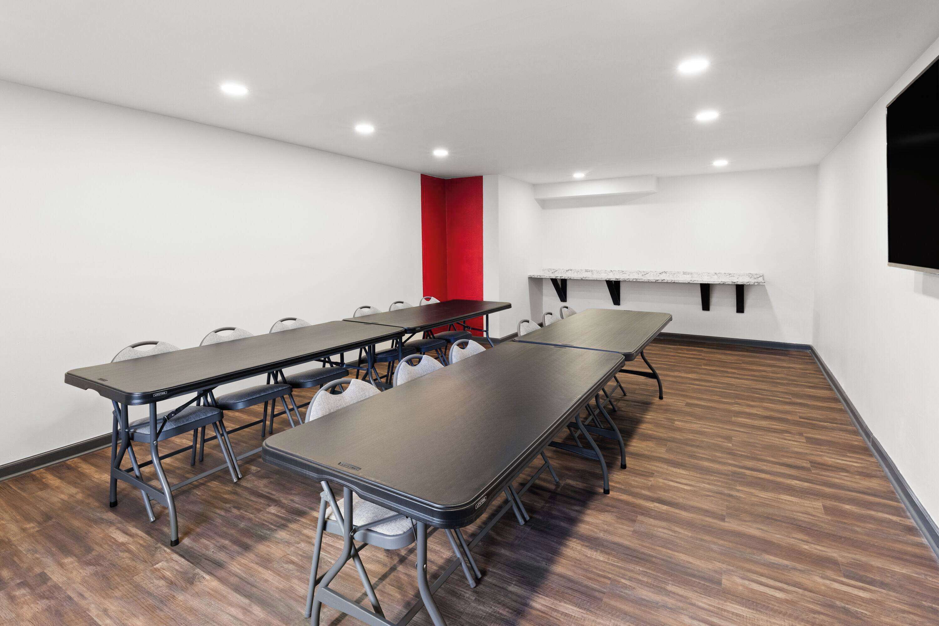 A conference room with a long table, chairs, and a red accent wall.