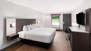 A modern hotel room with a large bed, bedside tables, a desk, and a television.