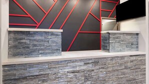 A reception area with a modern design, featuring a geometric pattern on the wall and a stone-textured counter. - Ramada by Wyndham Bainbridge (Bainbridge)