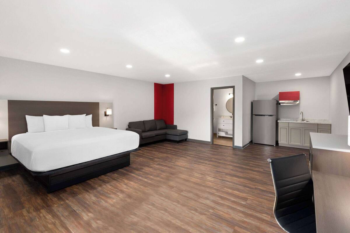 Quarto de hotel moderno com uma cama grande, um sofá, uma cozinha e uma mesa de jantar.