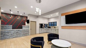 A modern hotel lobby with a reception desk, seating area, and a kitchen in the background. - Ramada by Wyndham Bainbridge (Bainbridge)