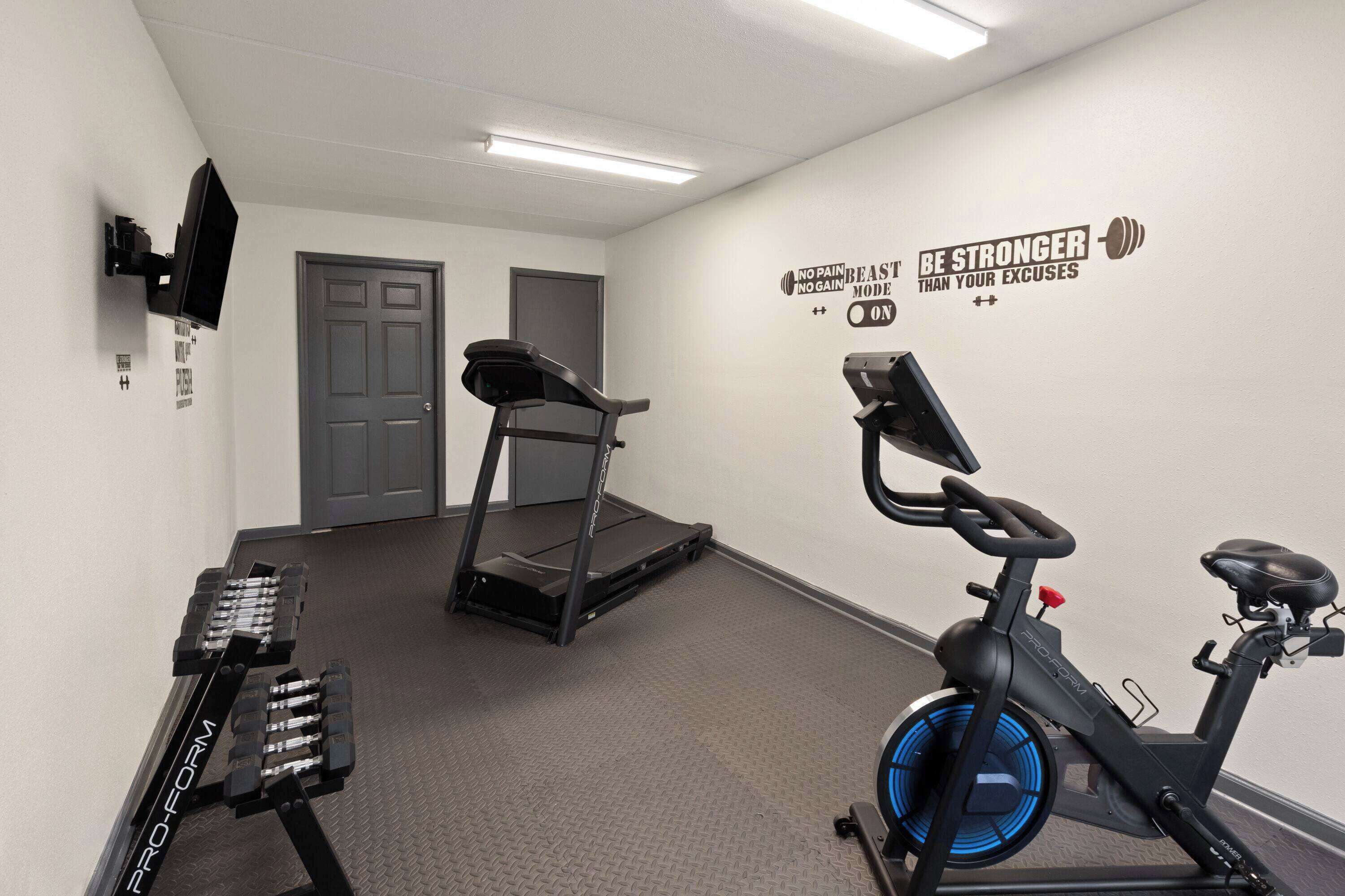 A fitness room with a treadmill, stationary bike, and weight bench.