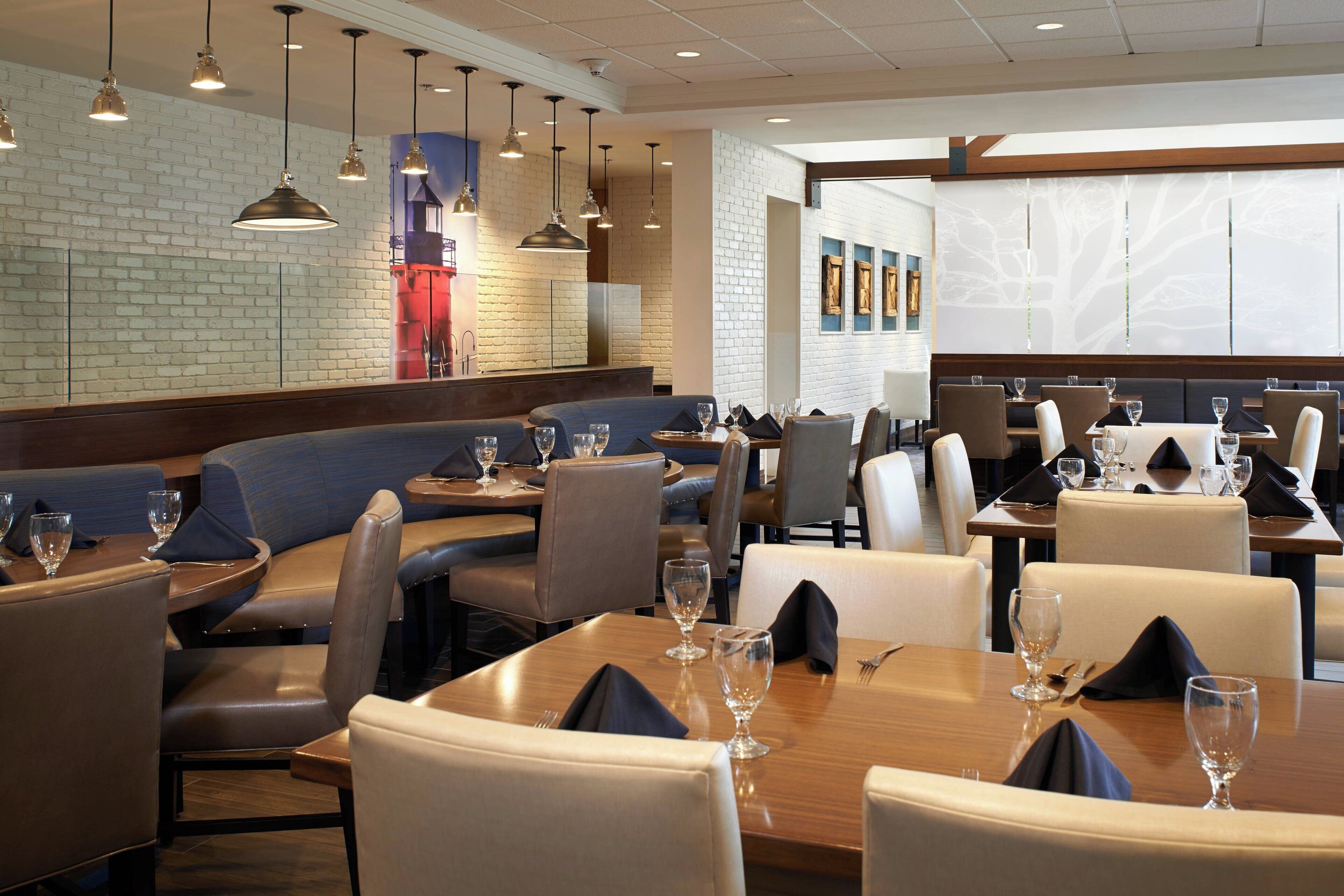 A restaurant with booths and tables, some with wine glasses and napkins.