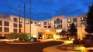 A multi-story hotel with a central entrance, flagpoles, and landscaped gardens. - Detroit Metro Airport Marriott (Romulus)
