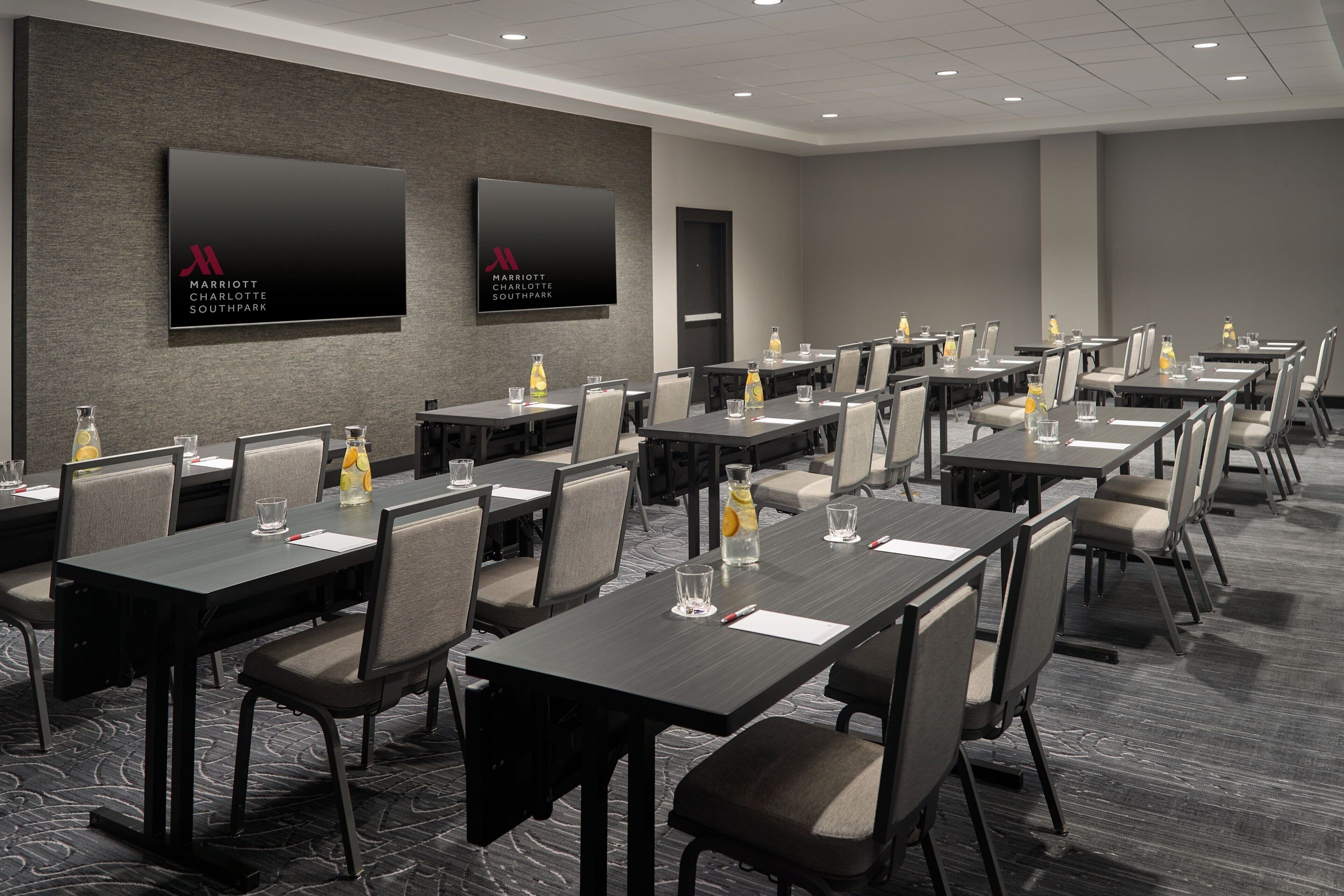 A conference room with multiple tables and chairs, equipped with water bottles and glasses.