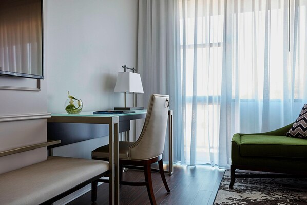 Una habitación de hotel moderna con escritorio, silla y sofá verde.