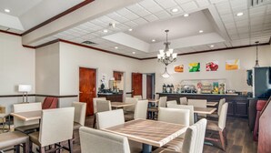 A hotel dining area with multiple tables and chairs, a bar, and a kitchen in the background. - Quality Inn Suwanee I-85 (Suwanee)