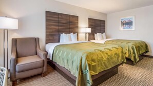A hotel room with a bed, two bedside tables, a chair, a lamp, and a framed picture on the wall. - Quality Inn Suwanee I-85 (Suwanee)