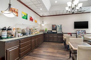A restaurant with a buffet, seating area, and a television.