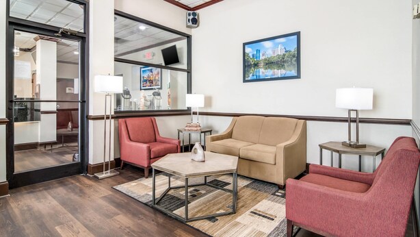 A hotel lobby with a sofa, armchairs, a coffee table, a TV, and a framed picture on the wall. - Quality Inn Suwanee I-85 (Suwanee)