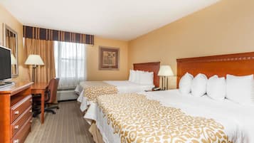 A hotel room with two beds, a desk, a chair, a television, and a window with curtains.