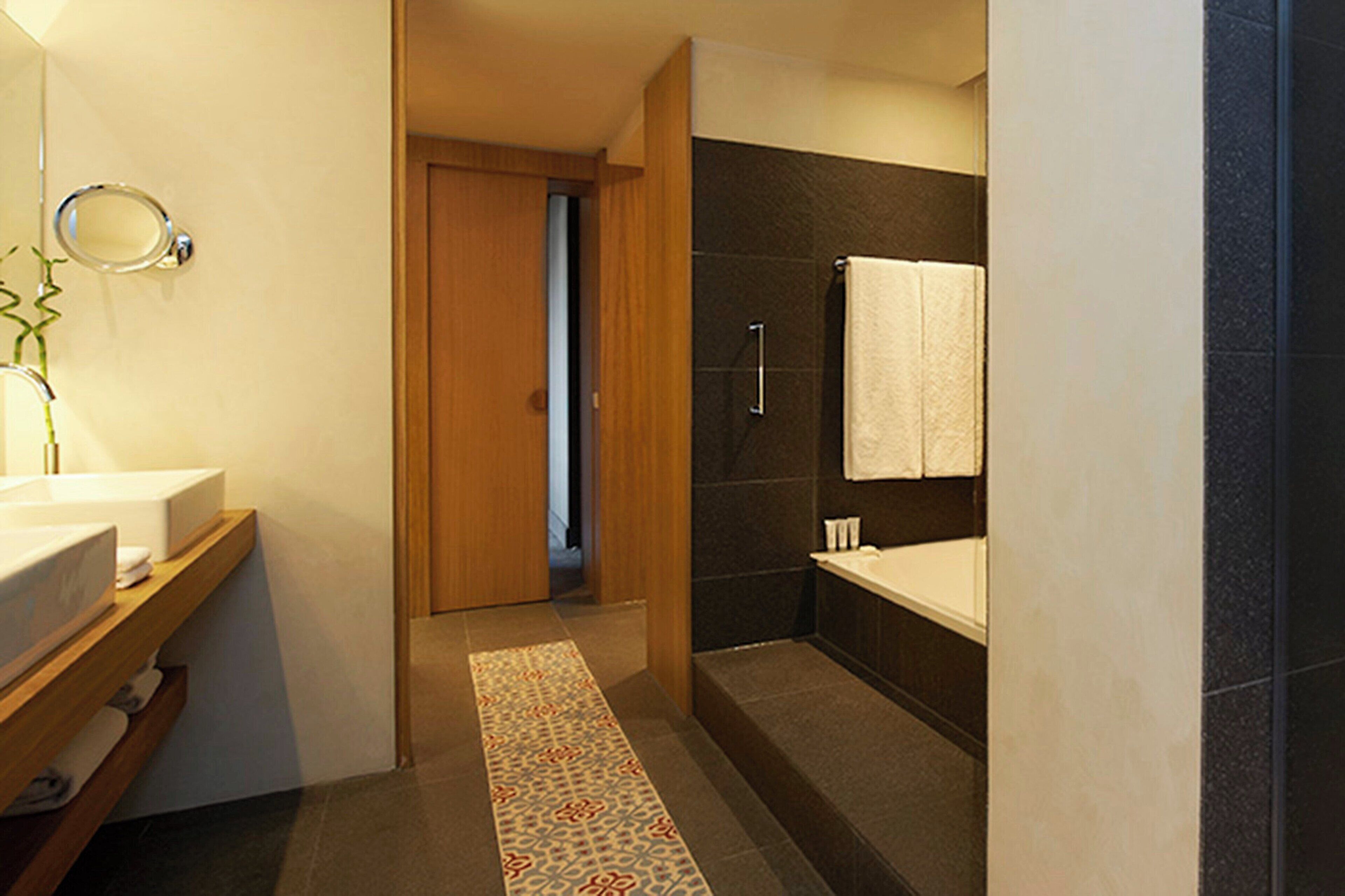 Un baño moderno con tocador de madera, ducha y toalla colgada en la pared.
