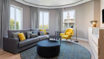 A modern living room with a grey sofa, yellow armchair, and a round ottoman.