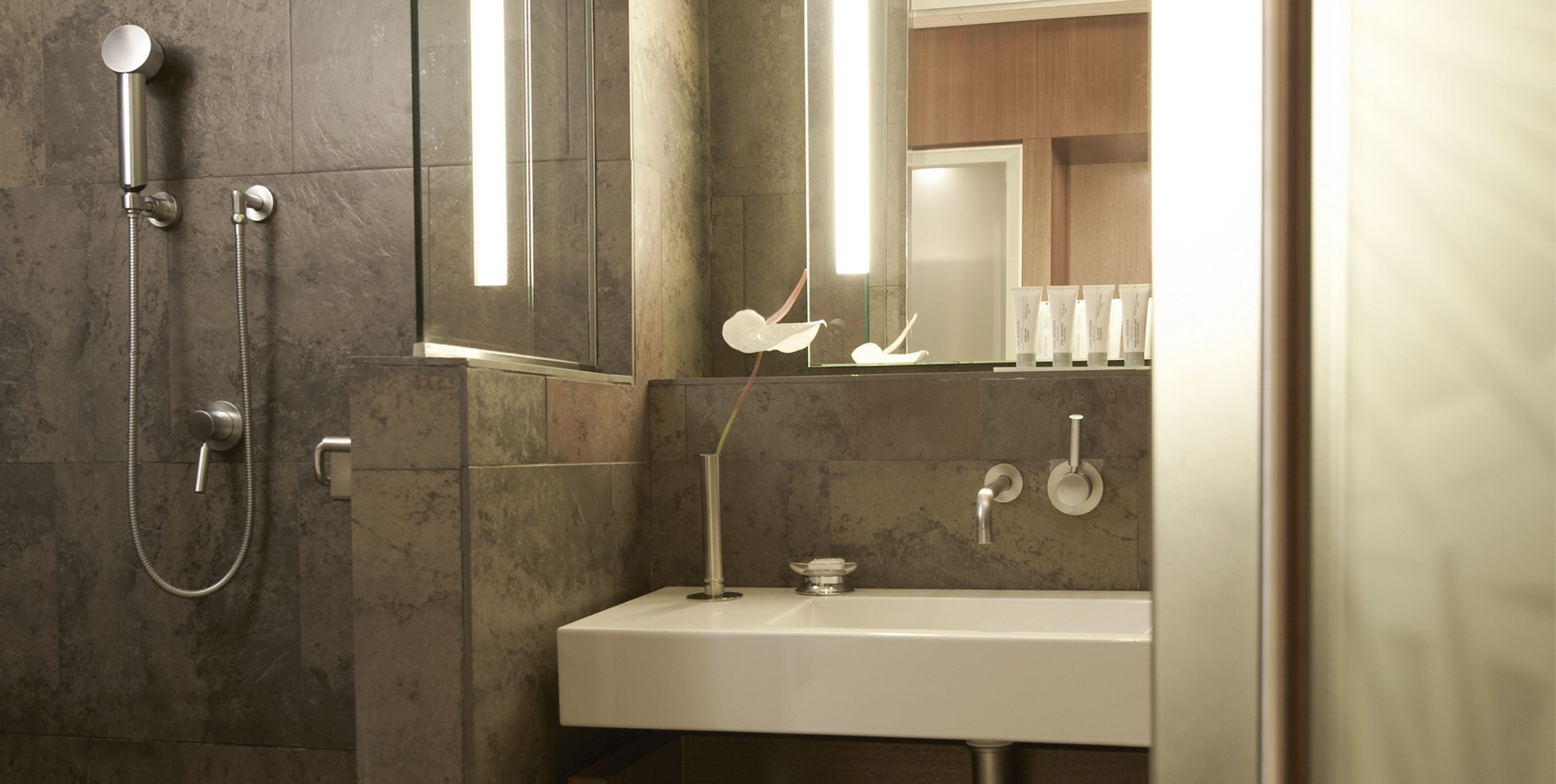 Un baño moderno con ducha, lavamanos y espejo.