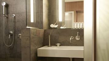 Un baño moderno con ducha, lavamanos y espejo.