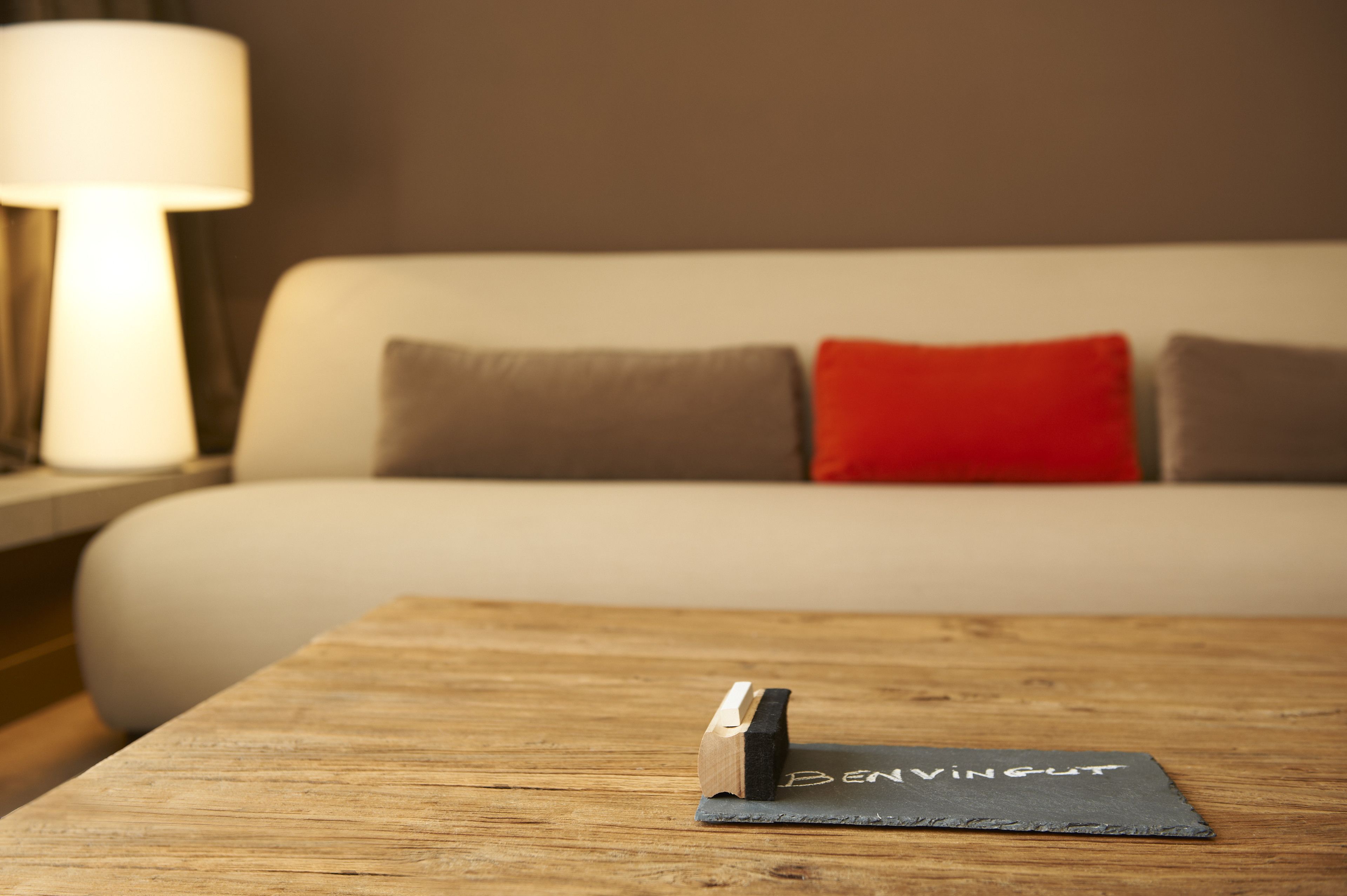 A wooden table with a black slate coaster and a wooden block with the text "BENVINGUT" on it.