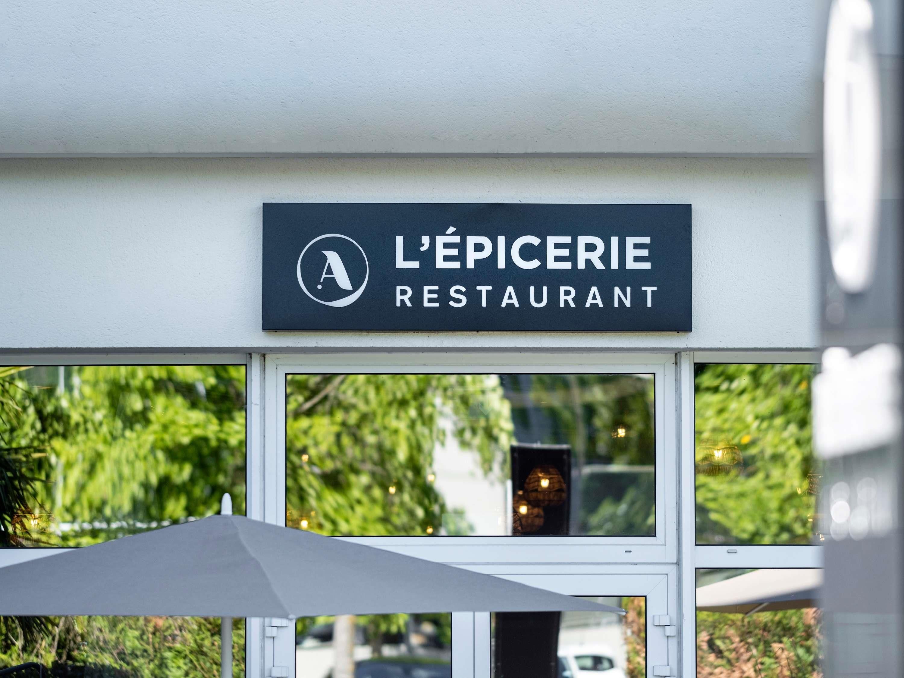 A restaurant sign with the name 'L'Épicerie Restaurant' and a logo.