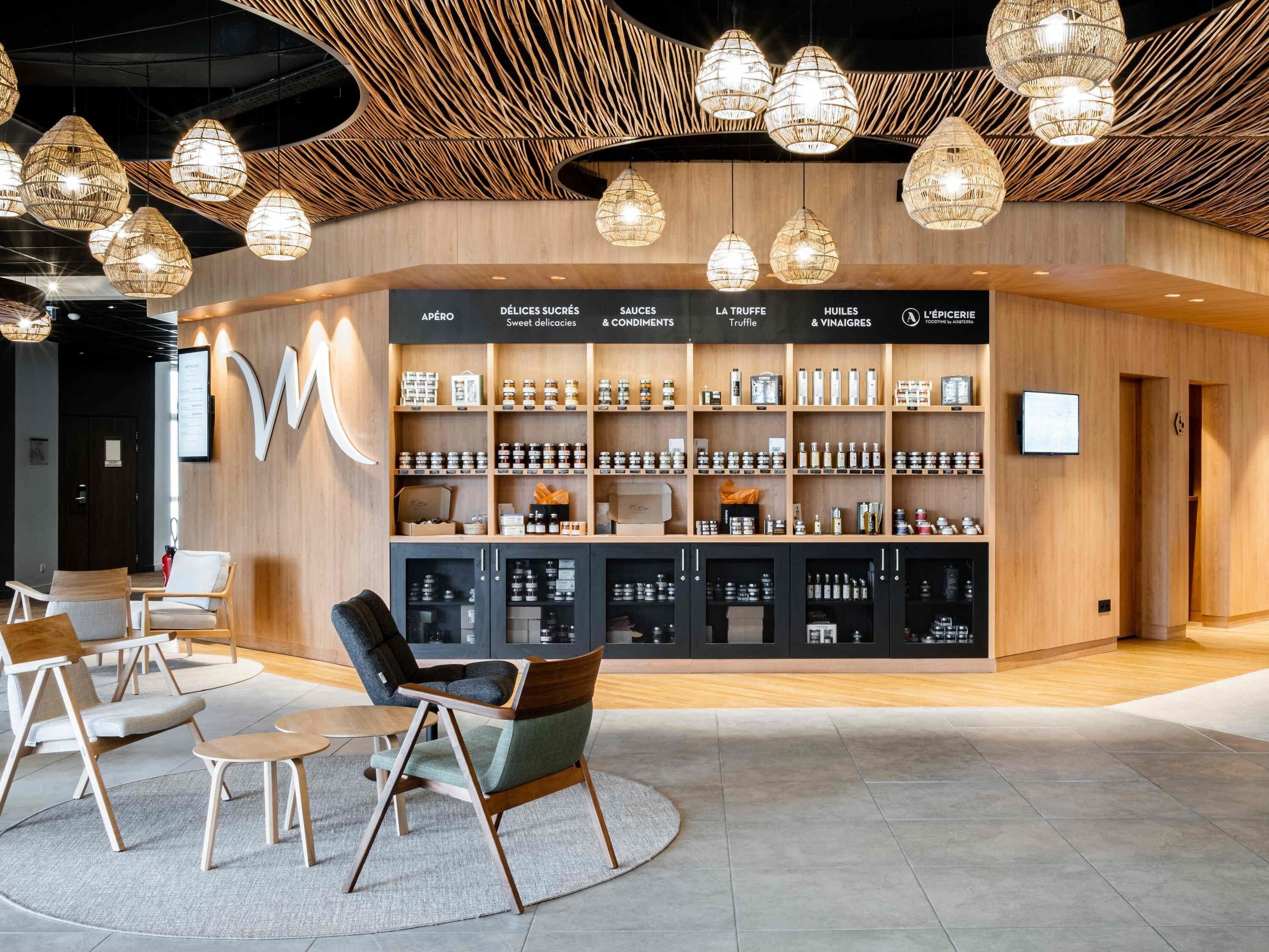 Un interior moderno con una presentación central de productos alimenticios, zona de estar y un diseño de techo único.