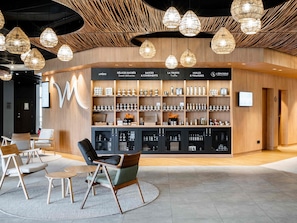 A modern interior with a central display of food products, seating area, and unique ceiling design. - Mercure Compiegne Sud (Lacroix-Saint-Ouen)