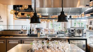 A modern kitchen with stainless steel appliances, hanging pendant lights, and a central island with wine glasses.