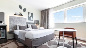 A modern hotel room with a neatly made bed, a small round table, and a view of the sky through a large window. - Mercure Compiegne Sud (Lacroix-Saint-Ouen)