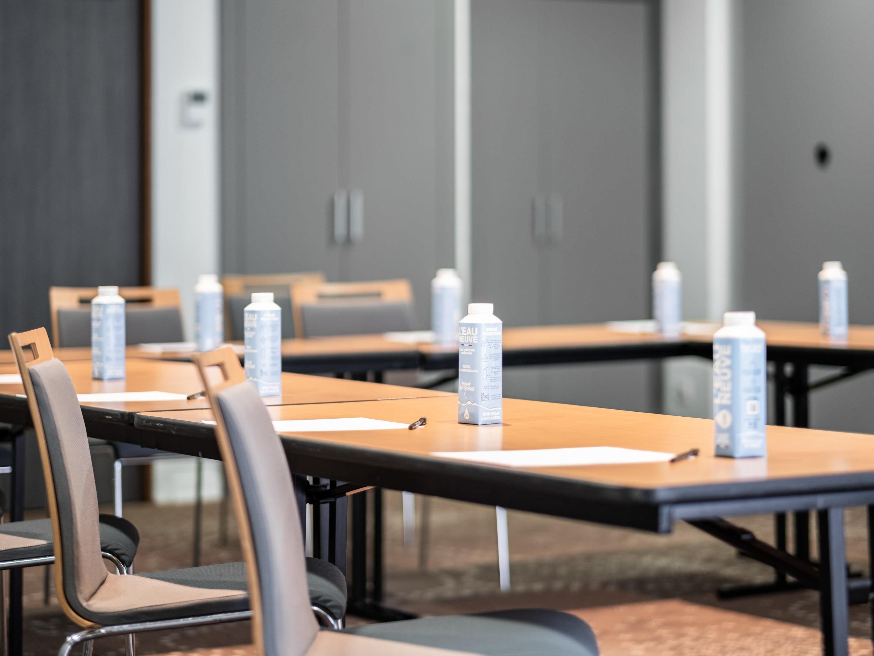Una sala de conferencias con mesas, sillas y botellas de agua.