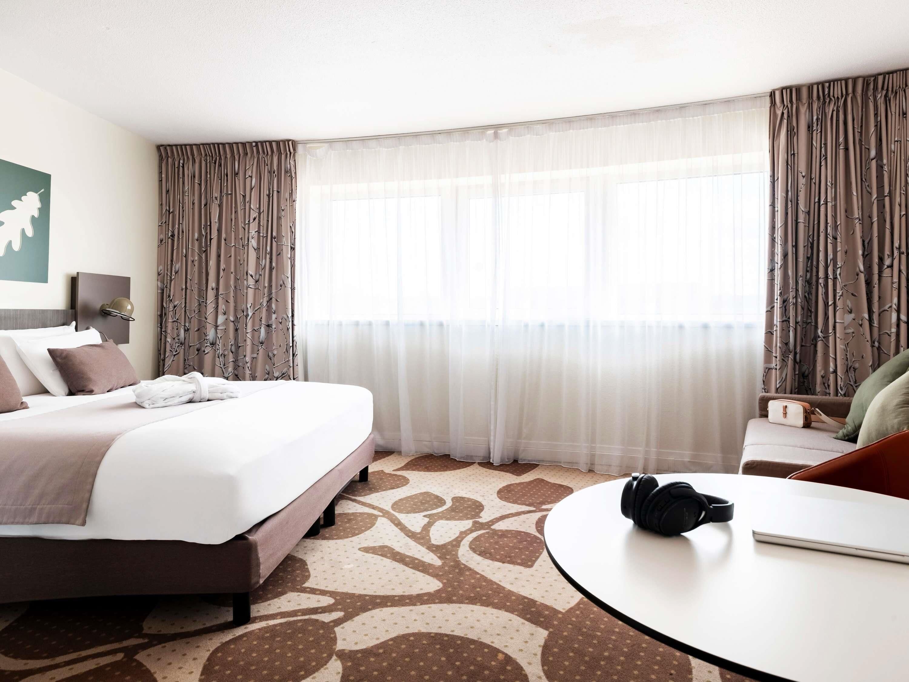 Una habitación de hotel con cama, una mesa redonda y auriculares, y una silla.