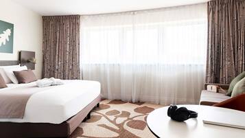 Una habitación de hotel con cama, una mesa redonda y auriculares, y una silla.